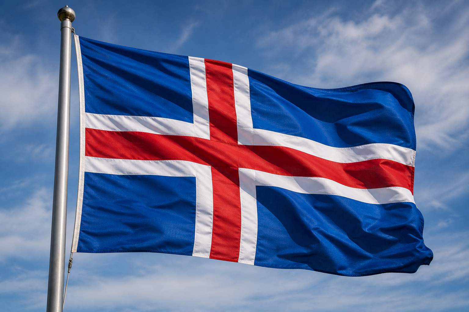 Nahaufnahme der wehenden Islandflagge an einem großen Metallmast vor hellem Himmel